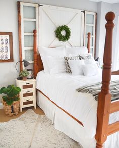 a bed with white sheets and pillows in a bedroom next to a dresser, mirror and potted plant