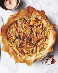 a quiche with bacon, cheese and spinach in a pie dish on a marble table