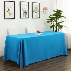 a blue table cloth with scalloped edges sits in front of three framed pictures on the wall