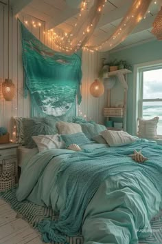 a bed with blue sheets and lights hanging from the ceiling in a room next to a window