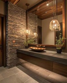 a bathroom with stone walls and lights hanging from the ceiling, along with a large mirror on the wall