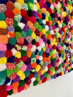 the colorful wall hanging is made out of pom - poms and yarns