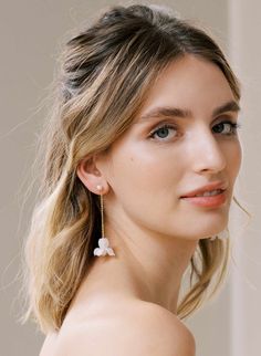 a woman with blonde hair and blue eyes is wearing white flowers on her earring