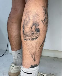 a man with a tattoo on his leg holding a parachute