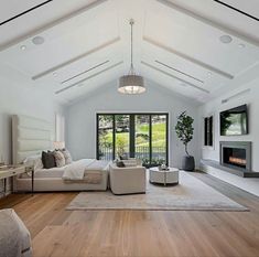 a large living room with white furniture and wood flooring on the wooden floor, along with an open fireplace