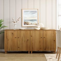 a wooden cabinet with plates and bowls on it in front of a white painted wall