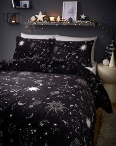 a bed covered in black and white stars and planets