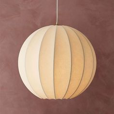 a large white paper ball hanging from a metal hook on a brown wall with a light fixture in the middle