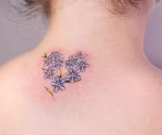 the back of a woman's neck with small blue flowers on her left side