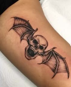 a skull and bat tattoo on the arm