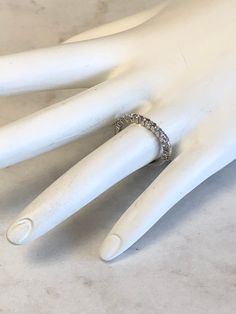 a white mannequin hand with a ring on it's left hand and a diamond band around the middle