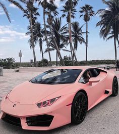 a pink sports car parked in front of palm trees