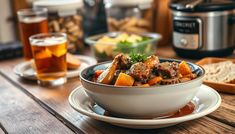 a bowl filled with meat and vegetables sitting on top of a table next to bread