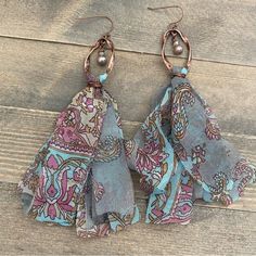 two pairs of blue and pink paisley fabric earrings on wooden floor with pearls hanging from them