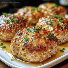 some meat patties on a white plate with parsley sprinkled on top