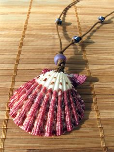 Ready for the Beach? Beautiful Purple Scallop shell is simply stunning!  This bold magenta pattern is the shell's natural color!  The front is very shiny,  it may have been polished or given a clear gloss finish.  I have topped it with one translucent matte bluish-purple glass pony bead and added three asymmetrically knotted white-striped opaque blue/purple glass E-beads.  I have strung and knotted them on waxed brown cotton cord creating a lightweight and comfortable adjustable necklace that is Summer Gift Round Bead Shell, Multicolor Shell Necklace As A Gift, Summer Gift Round Beads Shell, Summer Gift Pink Shell Necklace, Beachy Shell Beaded Necklaces As Gifts, Beachy Shell Beaded Necklace For Gift, Beachy Shell Beaded Necklaces For Gift, Bohemian Pink Shell As A Gift, Beachy Beaded Shell As Gift