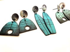 three pairs of earrings are shown on a white surface, one is blue and the other is silver