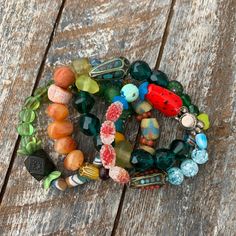 a bunch of different colored beads on top of a wooden table