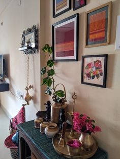 a table with vases and pictures on the wall