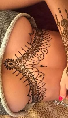 a woman's legs with henna tattoos on her stomach and the bottom half of her leg