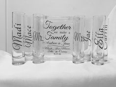 four personalized shot glasses sitting on top of a white tablecloth with black lettering