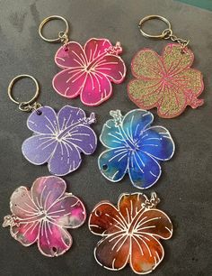 six flower shaped keychains are sitting on a counter top, each with different colors and designs