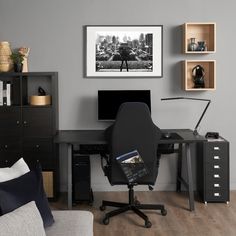 a black computer desk sitting in front of a wall with shelves on each side and a chair