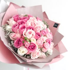 a bouquet of pink and white roses in a paper wrapper