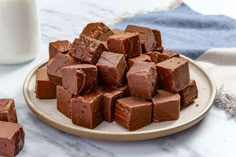 a plate full of chocolate pieces next to a glass of milk