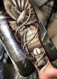 an arm tattoo with a dove and some words on it, as well as a candle