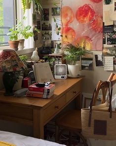 a room with many plants and pictures on the wall, including a desk in front of a window