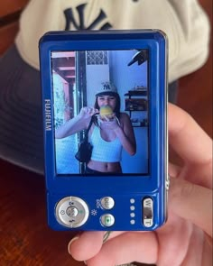 a person holding up a small blue device with a woman on it's screen