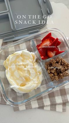 a plastic container filled with yogurt, strawberries and granola on top of a checkered table cloth