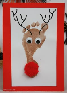 a reindeer handprinted on a card with red pom - pom balls