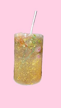 a glass filled with liquid and a straw sticking out of it's side on a pink background