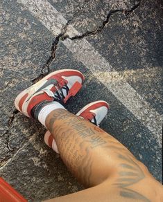 a person has tattoos on their legs and is standing in the middle of the street