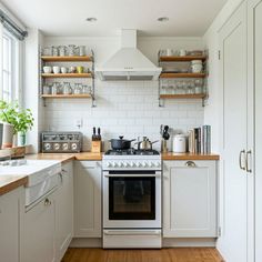 a kitchen with white cabinets and open shelvings on the wall above the stove