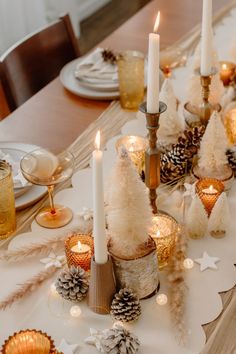 the table is set with pine cones and candles