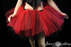 a woman wearing a red and black tutu skirt with her hands on her hips