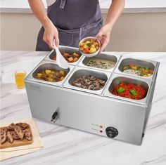 a person in an apron is serving food from a stainless steel dishwasher on a marble countertop