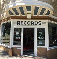 a record store with signs on the front door and in the window that says buy sell trade