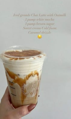 a hand holding up a cup of coffee with whipped cream and caramel drizzle