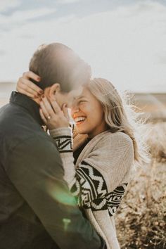 a man and woman standing next to each other in a field with the sun shining on them