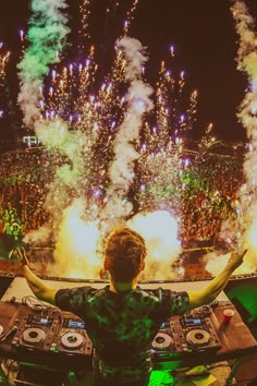 a man standing in front of a dj's set up at a party with fireworks