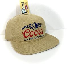 DETAILS: - Great-looking COORS BEER HAT for adults  - Tan with embroidered accents  - Officially licensed  - Unstructured crown with flat bill, retro 90s style   (new hat designed to look vintage) - Adjustable snapback - standard one size fits most adult  CONDITION: NEW WITH TAG   inventory ID#802401070TC2 Retro Dad Hat With Embroidered Logo, Vintage Flat Bill Dad Hat For Streetwear, Throwback Adjustable Hat With Curved Brim, Adjustable Curved Brim Throwback Hat, Adjustable Throwback Hat With Curved Brim, Vintage Snapback Hat For Baseball Season, Retro Hat With Embroidered Logo For Baseball Season, Retro Baseball Season Hat With Embroidered Logo, Retro Fitted Hat With Flat Bill