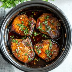 four cooked meats in a slow cooker with garnishes on top