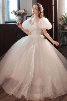 a woman in a white dress standing on a wooden floor