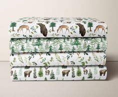 three sheets with deer and pine trees on them, one is white and the other is green