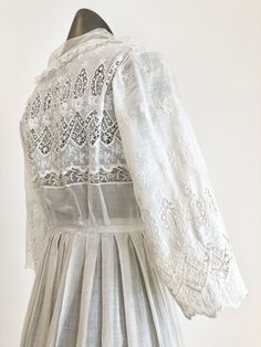 "Antique Edwardian white cotton lawn dress has eyelet lace embroidery throughout the bodice, sleeves, and around the hem. The dress has a ruffle trimmed net collar and net under bodice that has a crossover snap detail. The dress has snap and hook and eye closures at the skirt and bodice. Condition Overall excellent. There's a repair to the right sleeve, and orange stains near the seam. The front skirt has stains at the hem, the back skirt has some stains near the top of the lace, and yellowing a Classic Broderie Anglaise Dresses For Daytime, Classic Broderie Anglaise Dresses For Daywear, Classic Dresses With Broderie Anglaise For Daywear, White Lace Dress With Lace Cuffs For Summer, White Victorian Dress For Garden Party, Classic Broderie Anglaise Dresses, White Victorian Dress With Lace Trim For Garden Party, Broderie Anglaise Long Sleeve Day Dress, Lace Dress With Broderie Anglaise For Garden Party