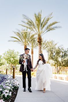 a bride and groom holding hands in front of palm trees